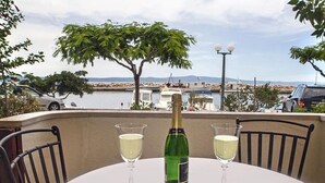 A table with a bottle of champagne and two glasses on a balcony overlooking a marina with boats and a body of water.