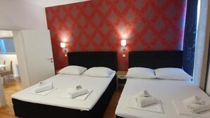 Hotellihuone, jossa on kaksi sänkyä, puulattia ja punakuvioinen seinä.