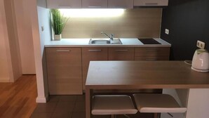 Pieni, käytännöllinen keittiö, jossa on pesuallas, työtaso ja puiset kaapit.