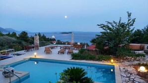 Ein Poolbereich mit Liegestühlen und Blick aufs Meer.