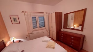 Ein Schlafzimmer mit Bett, Schminktisch, Spiegel und einem Fenster mit Vorhängen.