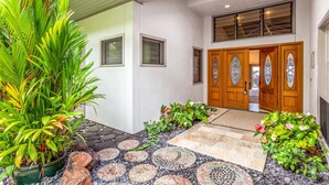 Una casa moderna con un camino de piedra que conduce a una puerta de madera con paneles de vidrio de colores.