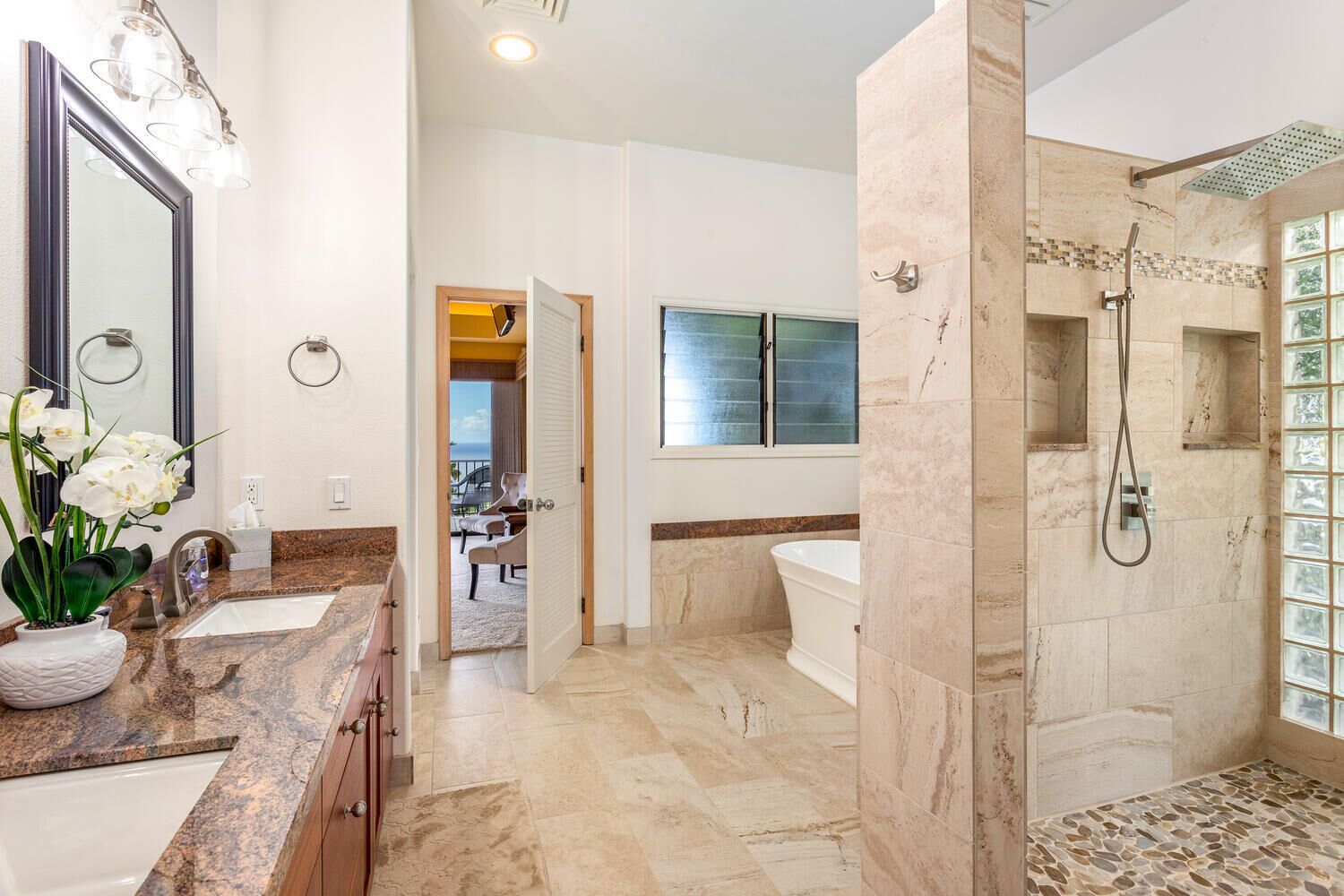A modern bathroom with a large mirror, two sinks, a bathtub, and a walk-in shower.