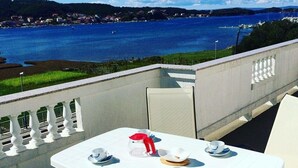 A balcony with a table set for two, overlooking a body of water and a distant shoreline. - Apartment in Supetarska Draga with Seaview, Balcony, Air condition, WIFI (4325-1) (Supetarska Draga)