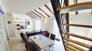 A dining area with a table and chairs, a kitchen in the background, and a staircase with wooden railings. - Apartment in Supetarska Draga with Seaview, Balcony, Air condition, WIFI (4325-1) (Supetarska Draga)