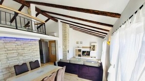 A modern kitchen with a dining area, wooden beams, a stone wall, and a view of the living area. - Apartment in Supetarska Draga with Seaview, Balcony, Air condition, WIFI (4325-1) (Supetarska Draga)