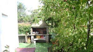 A patio area with a barbecue grill, surrounded by greenery and a small bridge. - Apartment in Lopar with Terrace, Air condition, WIFI (568-4) (Lopar)