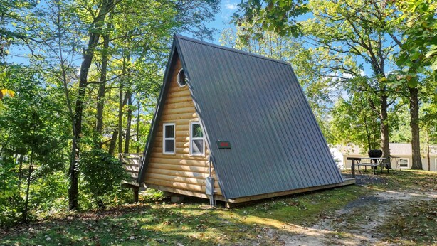 A small, wooden cabin with a sloped roof, surrounded by trees. - A-Frame Tiny House Tucked into the Northwoods (Walker)