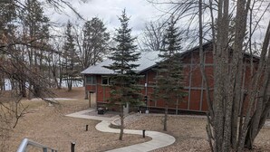 A building with a metal roof, surrounded by trees and a pathway leading to it. - A-Frame Tiny House Tucked into the Northwoods (Walker)