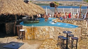A pool area with stone walls, a thatched roof, and outdoor seating. - Apartment in Novalja with Seaview, Terrace, Air condition, WIFI (3565-1) (Novalja)