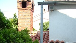 A courtyard with a stone wall, a brick chimney, and a tiled roof. - Apartment in Kampor with Balcony, Air condition, WIFI, Washing machine (895-4) (Kampor)
