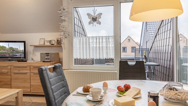 Een moderne keuken met een televisie, houten kastjes en een eethoek met een ontbijt gedekte tafel.