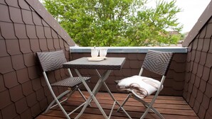 Een klein balkon buiten met een tafel en twee stoelen.