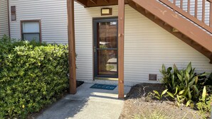Une entrée d’immeuble avec un escalier en bois, une porte et une petite fenêtre.