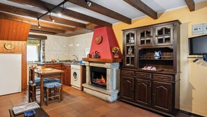 Eine Küche mit Kamin aus Stein, Holzbalken und einer eingebauten Kabine mit Glastüren.
