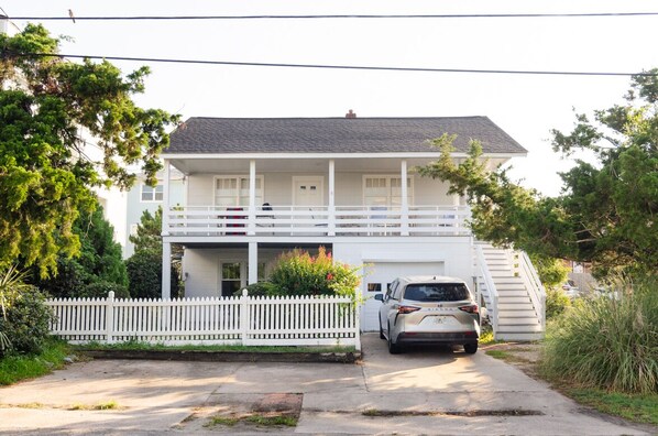 A two-story house with a white exterior, a front porch, and a staircase leading to the second floor.