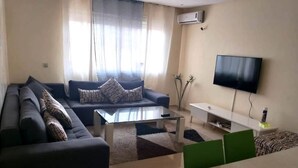 Un soggiorno moderno con divano, tavolino e televisore a schermo piatto fissato al muro.