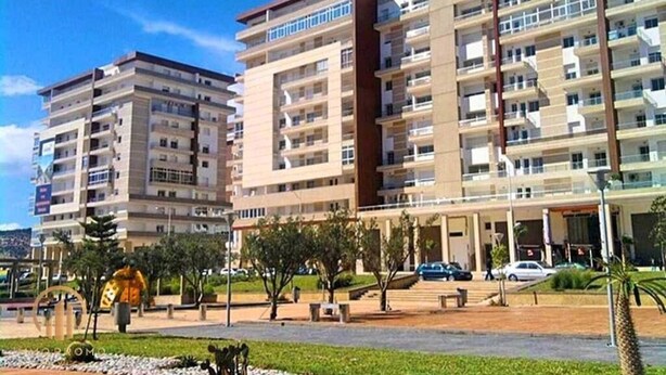 Un edificio residenziale a più piani con balconi, un cortile centrale e un’area di parcheggio.