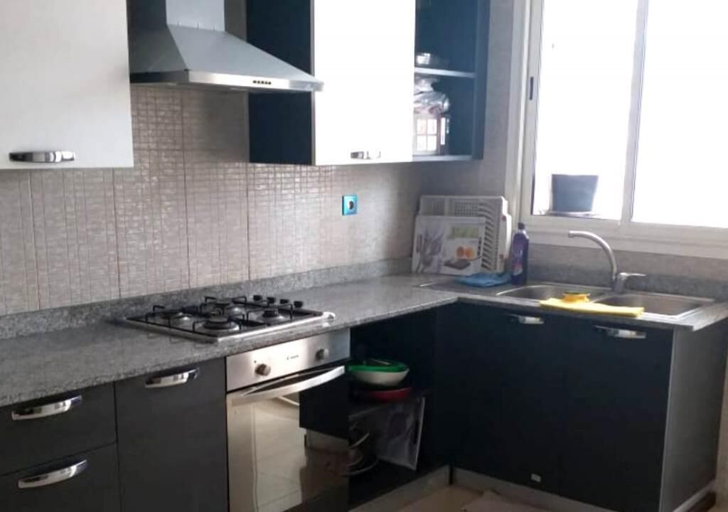 A kitchen with a gas stove, stainless steel appliances, a sink, and cabinets.