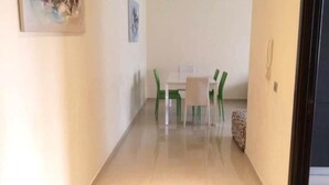Un corridoio con zona pranzo, tavolo e sedie.