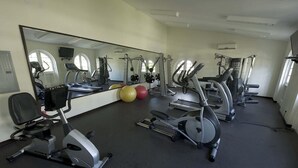 Ein Fitnessraum mit Trainingsgeräten, einem großen Spiegel und Trainingsbällen.
