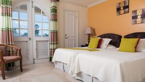 A hotel room with two beds, a wooden chair, a door with a view, and a lamp. - Modern Beachfront Condo with Pool - Sapphire 118 (Saint Lawrence Gap)