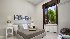 Una camera da letto con un letto, comodini, una finestra vista e quadri appesi al muro.