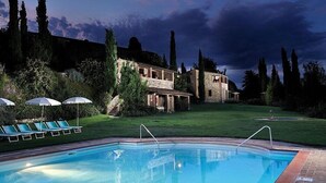 A pool area with lounge chairs and a stone building in the background.