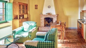 A cozy living room with a fireplace, checkered sofas, and a dining area.