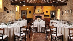 A restaurant with high wooden ceilings, stone walls, and multiple tables set for dining.