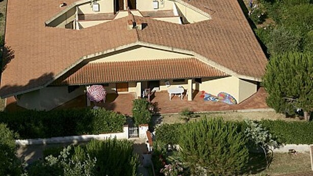 Ein Haus mit geneigtem Dach, einer überdachten Veranda und einer Flagge davor.