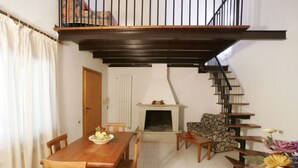 Ein Essbereich mit Holztisch und -stühlen, einem Kamin, einer Treppe und einer Blumenkomposition.