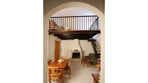 Ein Essbereich mit Holztisch und -stühlen, einem Kamin und einer Treppe, die zu einer oberen Ebene führt.