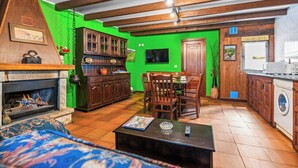 Een gezellige woonkamer met een open haard, houten meubels en een groene accentmuur.