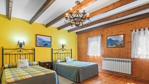 Een kamer met twee bedden, houten vloeren, een kroonluchter en een radiator.