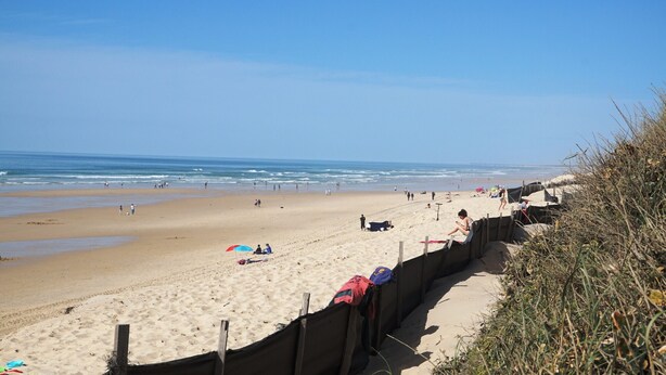 A sandy beach with a wooden fence, some beachgoers, and the ocean in the background. - Maison 4 chambres proche plage (023) (Biscarrosse)