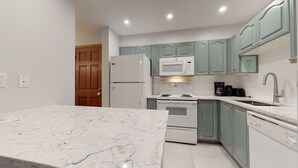 Une cuisine moderne avec des appareils électroménagers blancs, un plan de travail en marbre et des meubles de couleur turquoise.