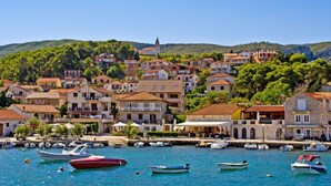 A coastal town with buildings along the waterfront, boats docked, and a prominent church on a hill. - Apartment in Jelsa with Terrace, Air condition, WIFI (3621-2) (Jelsa)