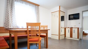 Et lille hotelværelse med spisebord, stole, et skab og et fjernsyn.