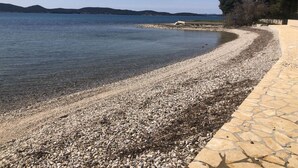 A pebble beach with clear water and a stone pathway. - Apartment in Sukošan with Seaview, Terrace, Air condition, WIFI (3495-5) (Sukošan)