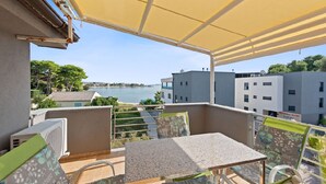 A balcony with a table and chairs, overlooking a body of water and buildings. - Apartment in Sukošan with Seaview, Terrace, Air condition, WIFI (3495-5) (Sukošan)