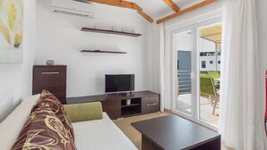 A modern hotel room with a wooden ceiling, a flat-screen TV, a sofa with patterned cushions, a small table, and a sliding glass door leading to an outdoor area. - Apartment in Sukošan with Seaview, Terrace, Air condition, WIFI (3495-5) (Sukošan)