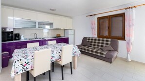 Un espacio habitable compacto con kitchenette, comedor y sofá.