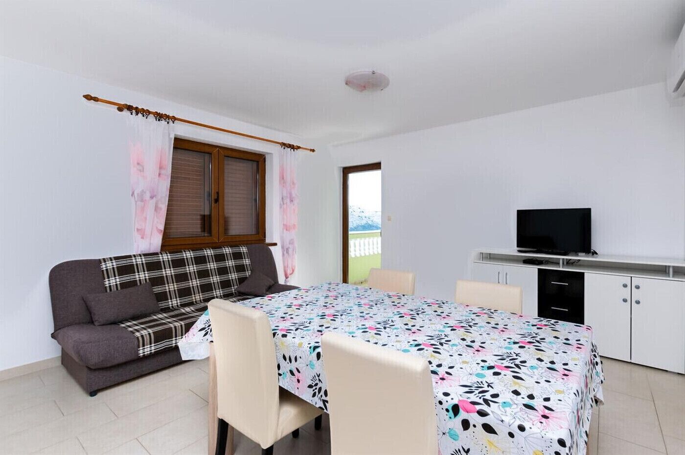 A small, clean room with a sofa, a table, and a TV.