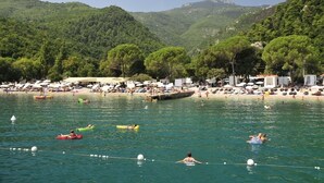 Une plage où l’on peut se baigner et prendre des bains de soleil, entourée de collines verdoyantes.