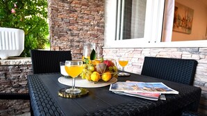 A table set with a fruit bowl, glasses of orange juice, and a magazine.