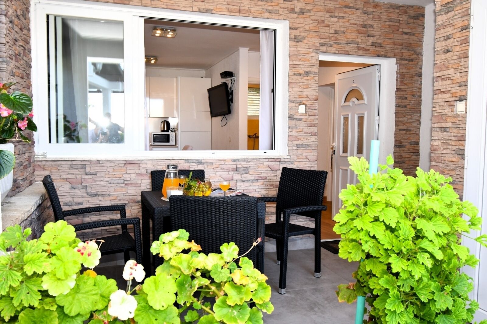 An outdoor seating area with a table and chairs, a stone wall, and potted plants.