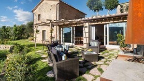 Une maison de campagne en pierre dotée d’un patio couvert, aménagé avec du mobilier d’extérieur et un foyer.