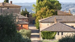 Un village traditionnel avec des bâtiments aux toits de tuiles en terre cuite, une allée centrale et une vue sur des collines lointaines.