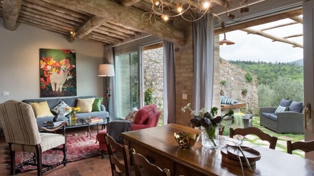 Un intérieur rustique comprenant un coin repas, un ensemble de canapés et un tableau représentant un lama.